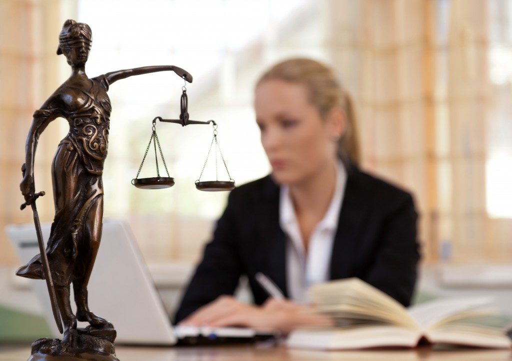 Statue of justice with lawyer typing in the background