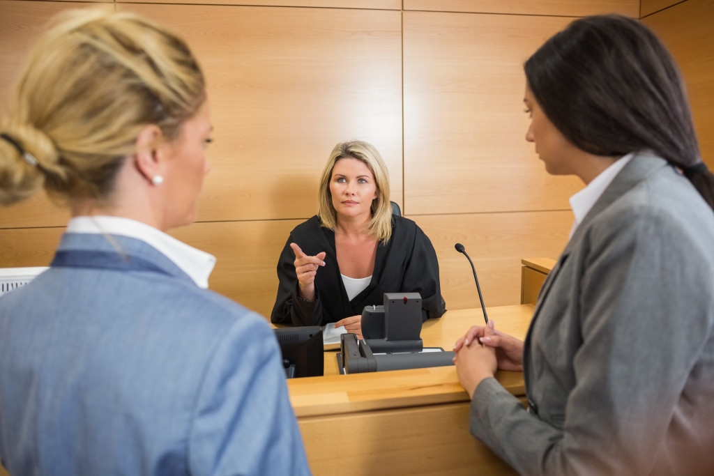 A judge talking to two lawyers in a courtroom.