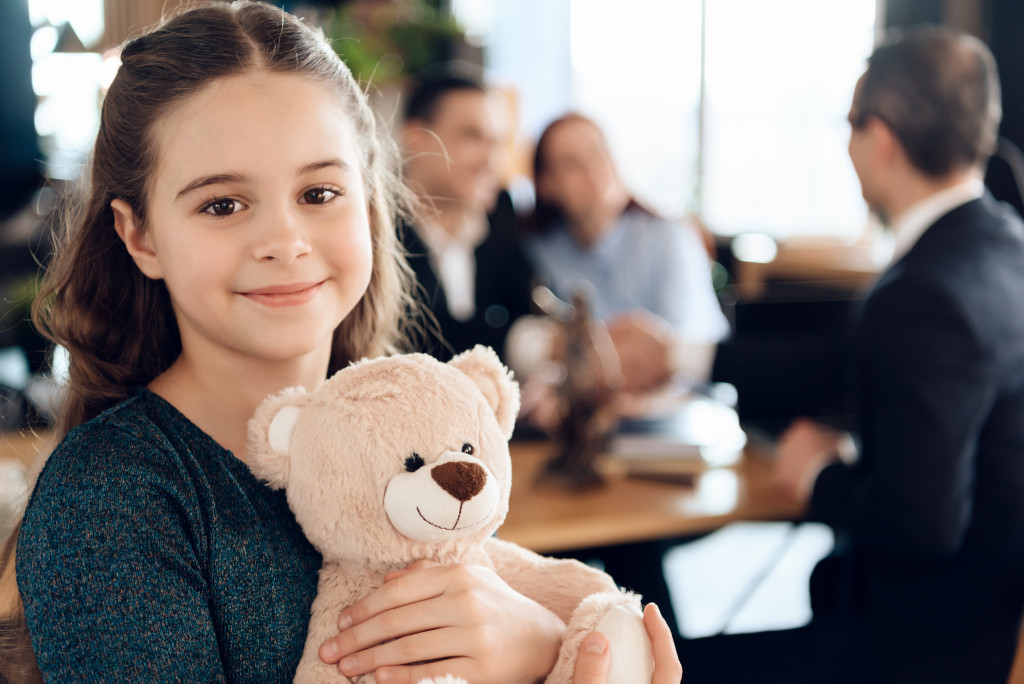 A child in an office holding a teddy bear