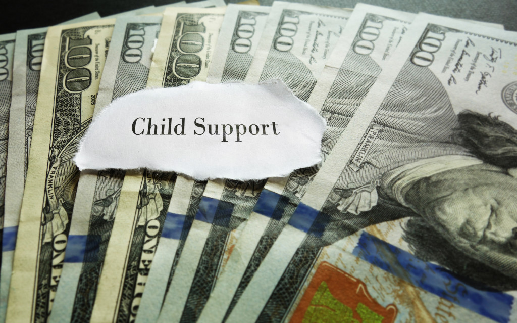 bunch of money with teared piece of paper with child support on top